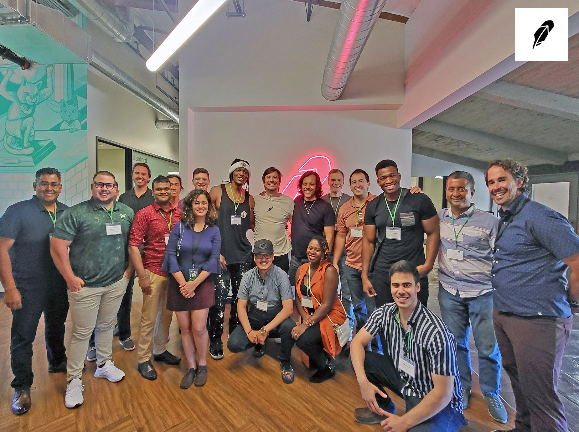 Robinhood founders and UX'ers poses in an office, with some standing and others crouching on a wooden floor.